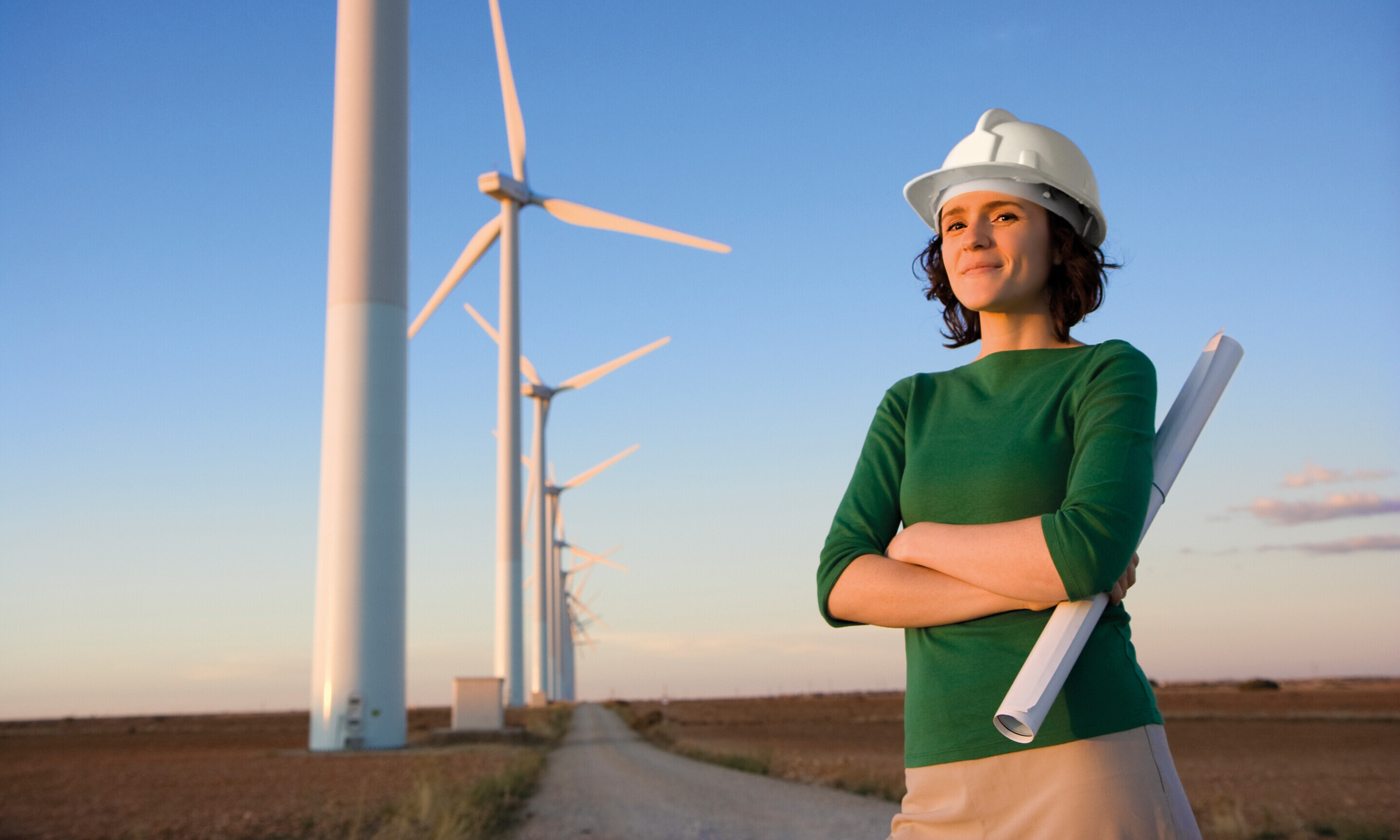 Frau mit Helm vor Windenergie-Anlage