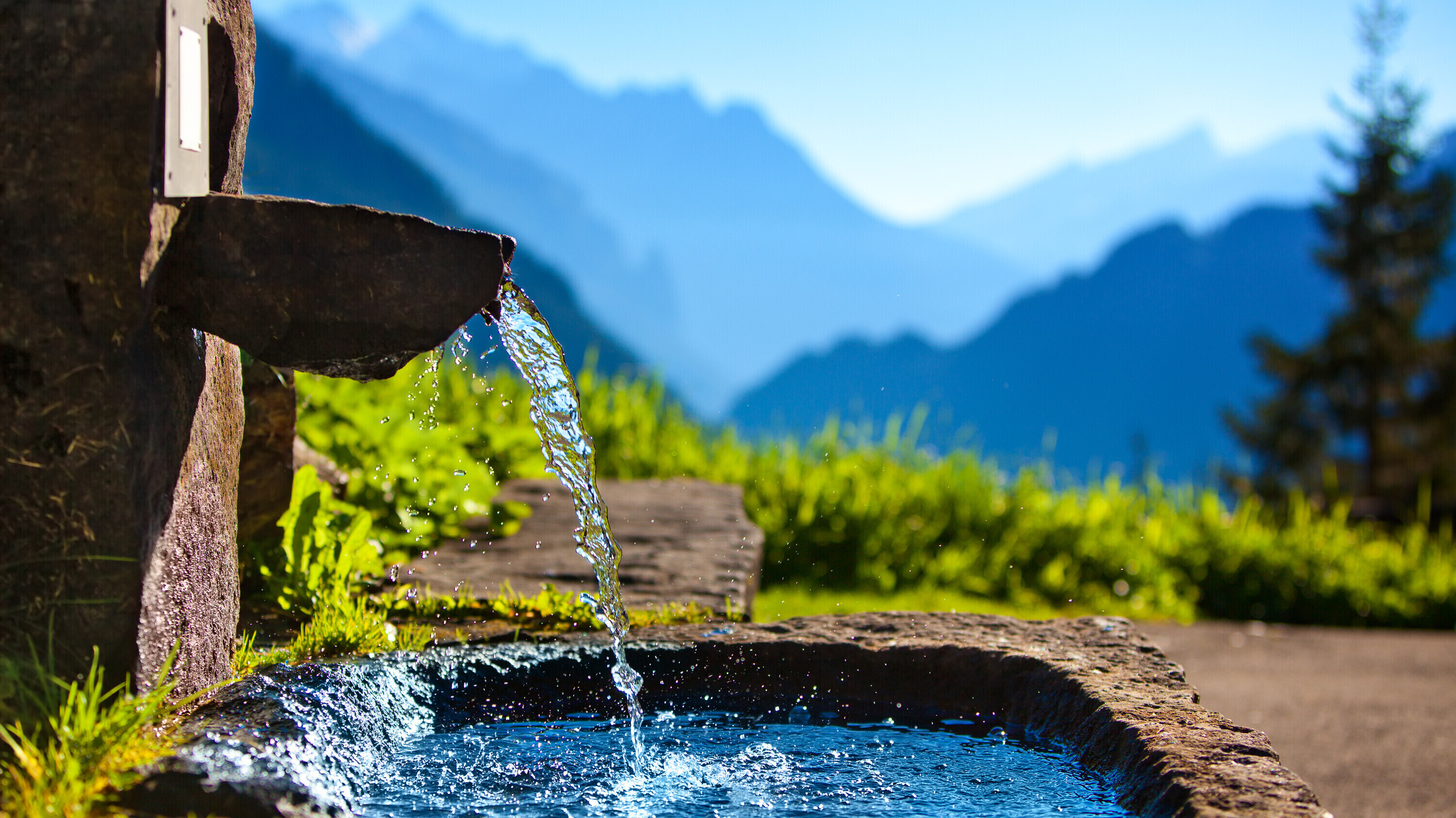 Bild eines Brunnens vor Bergkulisse