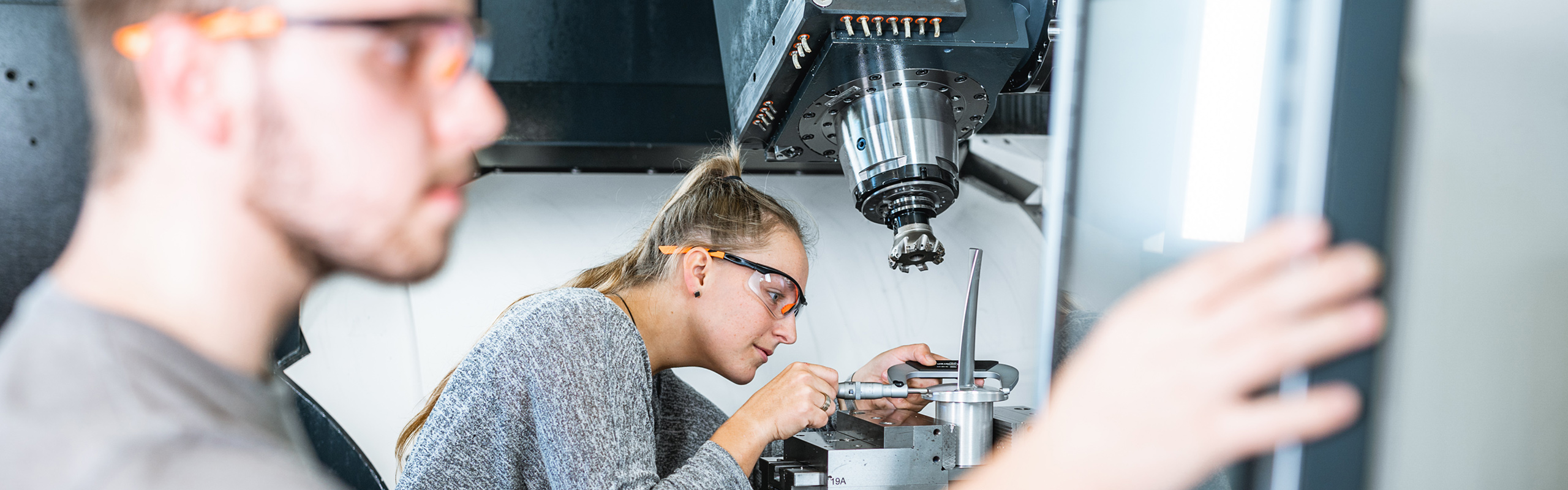Studierende der Maschinentechnik neben einer Fräsmaschine