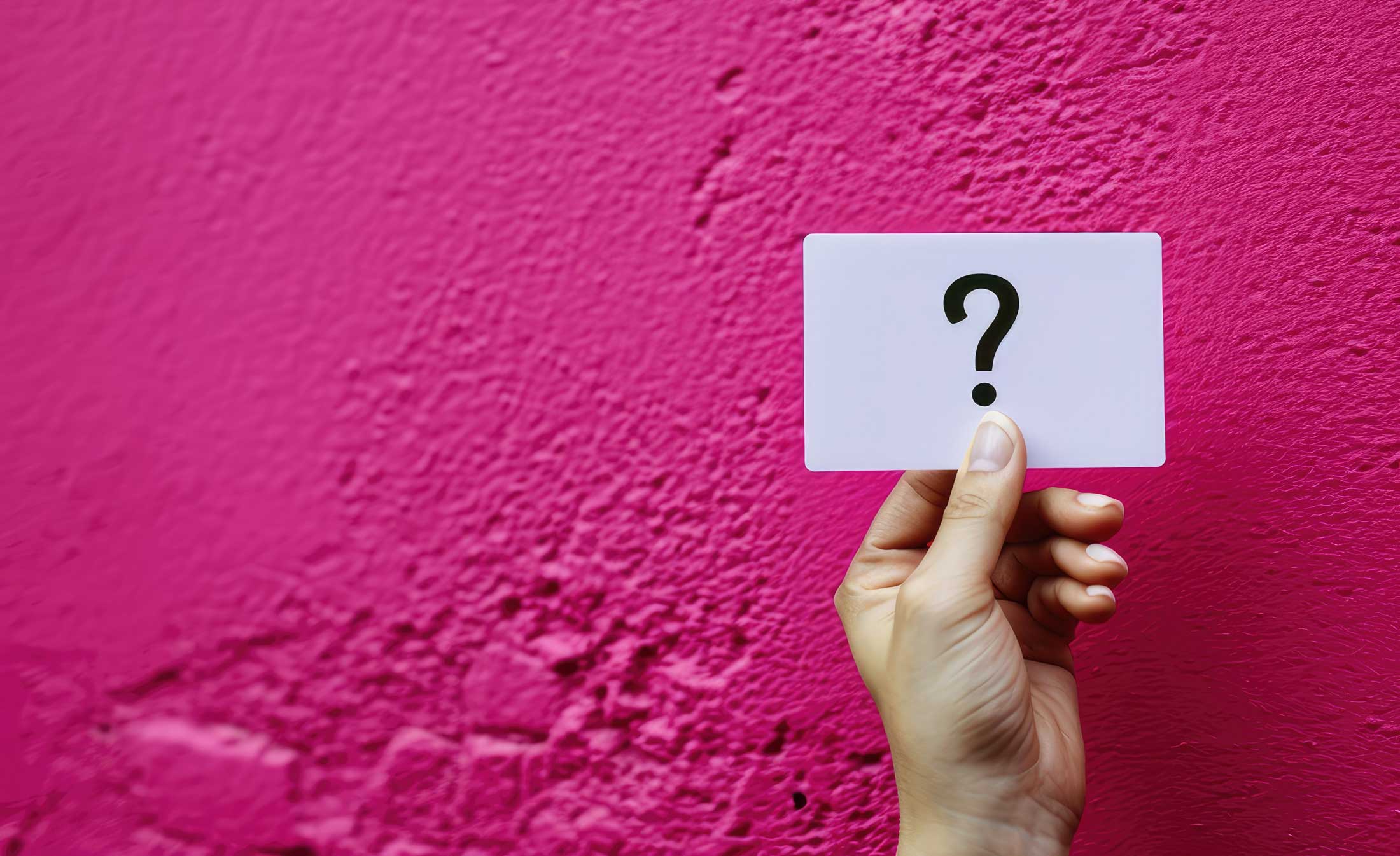 Hand hält eine Karte mit einem Fragezeichen als Symbol für FAQ