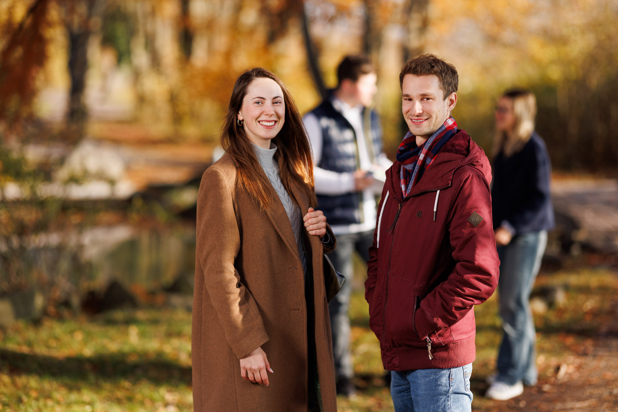 junge Frau und junger Mann mit zwei unscharfen Menschen in herbstlichem Wald