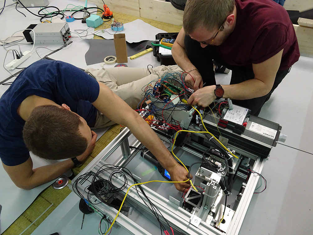 Studierende montieren das Innenleben eines frühen Prototyps des Flachdach-Roboters.